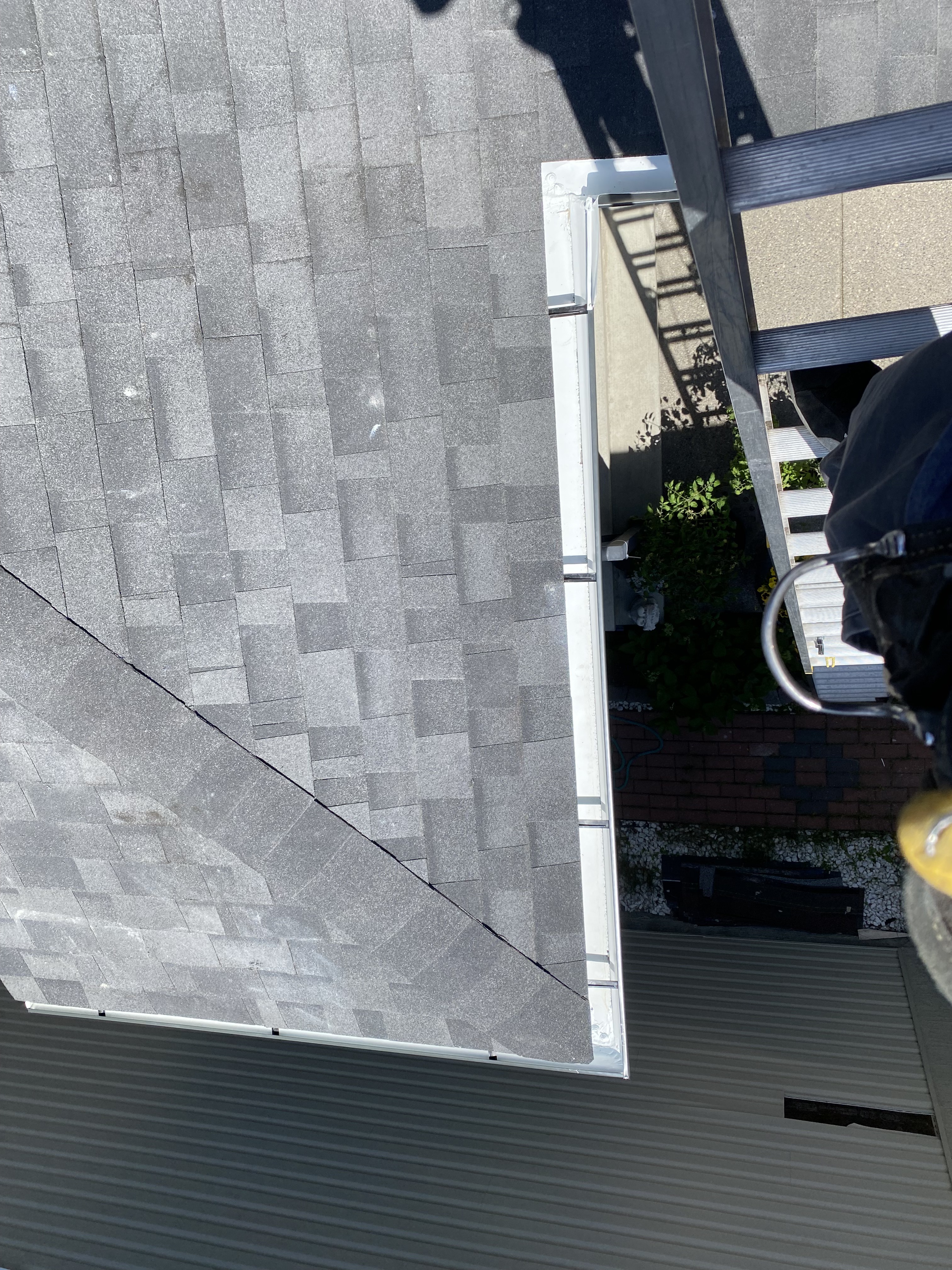 New eavestrough installation along roof shingles