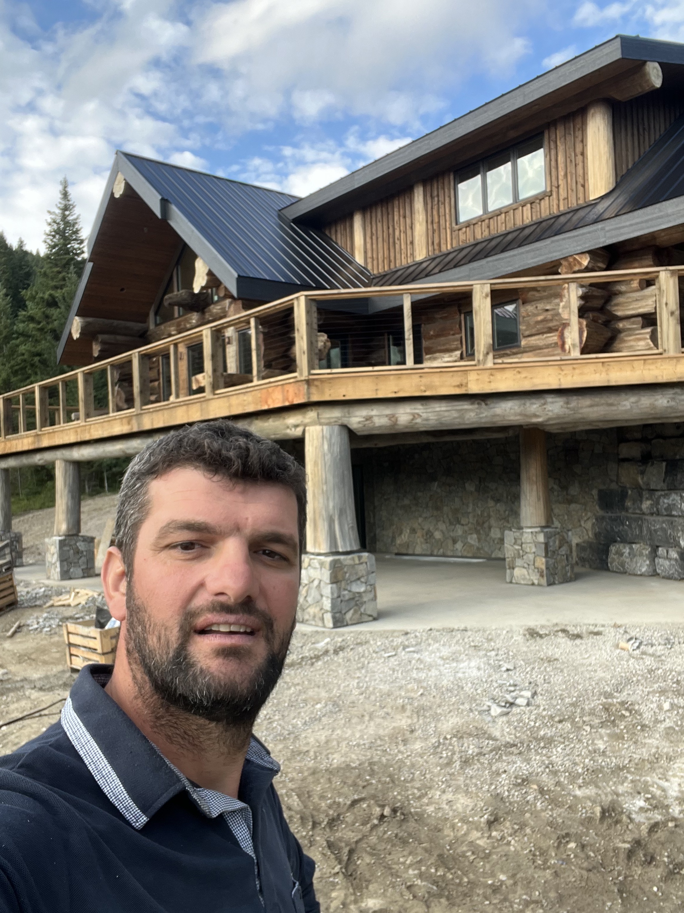 Owner Nick at a completed log home with stone base