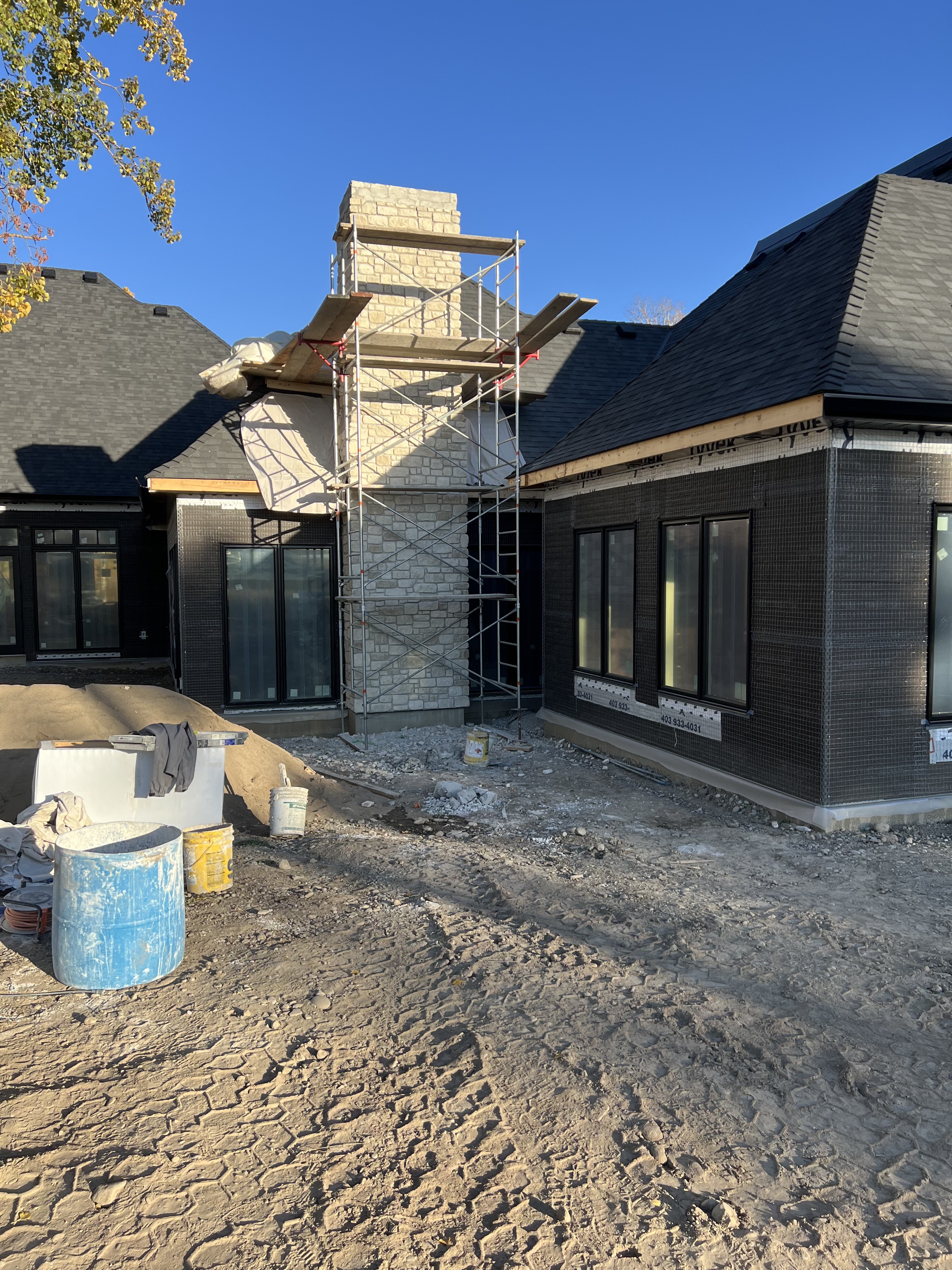 Stone chimney installation on black brick home