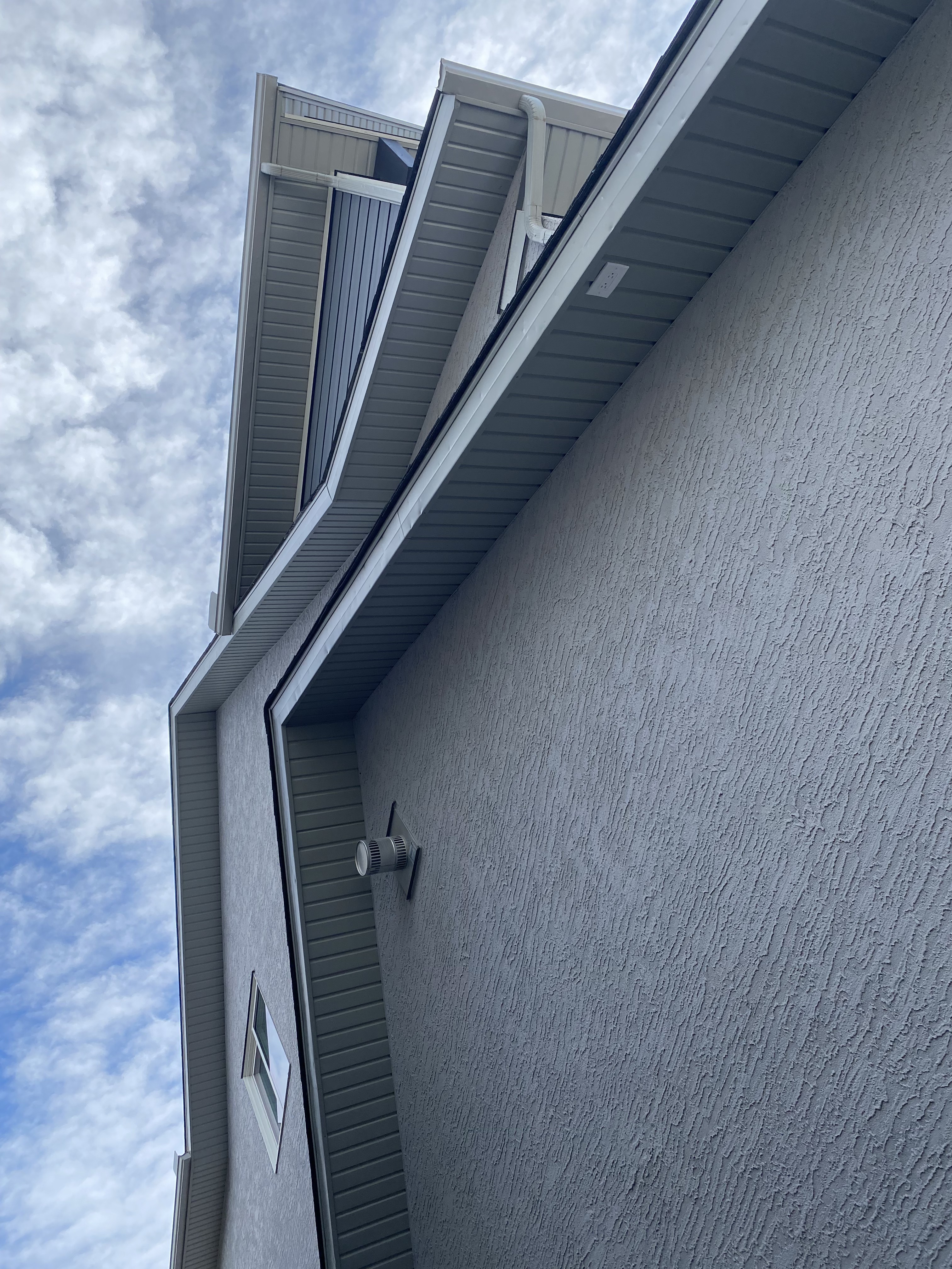 Hail-damaged fascia and stucco detail before replacement